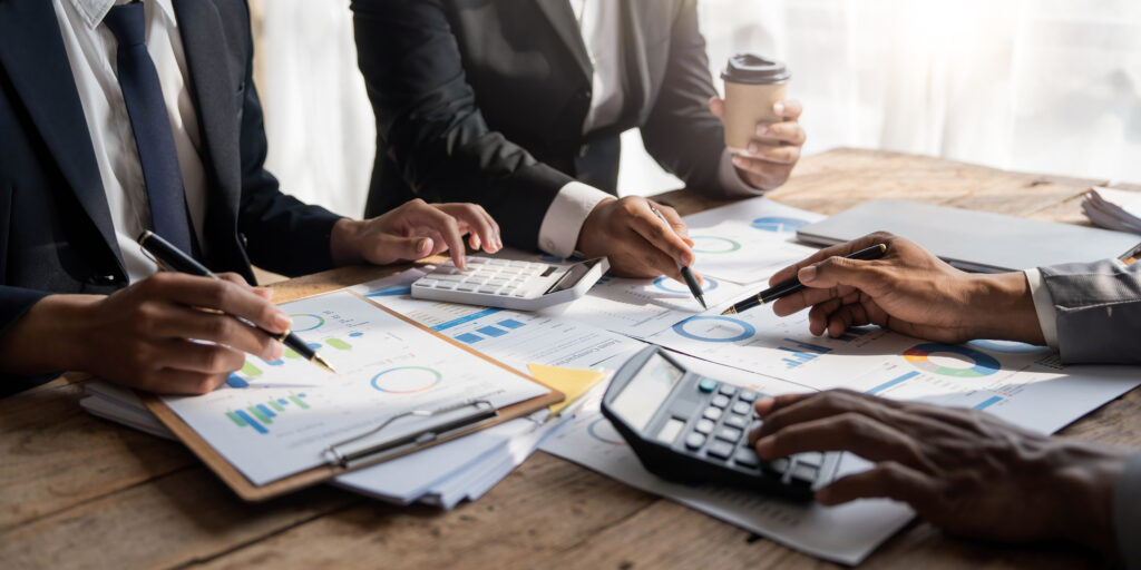 Business People Meeting using laptop computer,calculator,notebook,stock market chart paper for analysis Plans to improve quality next month. Conference Discussion Corporate Concept